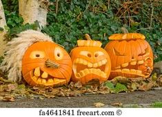 three carved pumpkins sitting on the ground