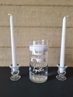 three glass candles are sitting next to each other on a black surface with a beige wall behind them