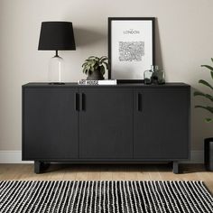 a black sideboard with two doors and a lamp on top in a room next to a rug