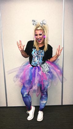 a woman with her hands in the air while wearing a purple and blue tutu skirt