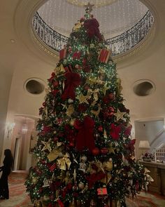 a large christmas tree in the middle of a lobby with red and gold decorations on it