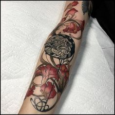 a woman's arm with tattoos on it and flowers in the middle of her arm