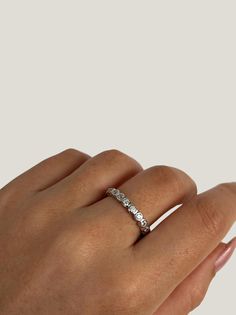 a woman's hand with a diamond ring on top of her finger, wearing a white gold band