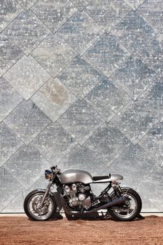 a motorcycle parked in front of a wall with a diamond pattern on it's side