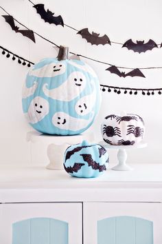 a white cabinet topped with blue and black pumpkins next to bats hanging from the ceiling