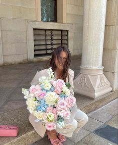 a woman sitting on the ground with a bouquet of flowers in front of her face