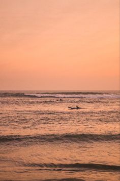 two surfers in the ocean at sunset