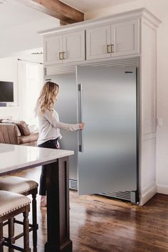 a woman standing in front of a refrigerator