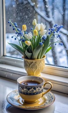 a cup and saucer with flowers in it sitting on a window sill