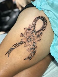 a woman's thigh with a tattoo design on it and flowers in the middle