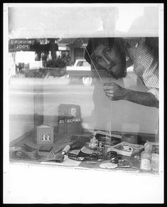 a man looking through a window at some items on the table in front of him