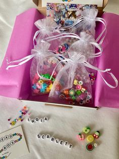 a pink box filled with lots of colorful beads and buttons on top of a table