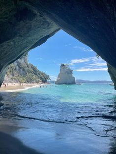 people are swimming in the blue water near an ocean cave