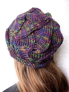 a woman wearing a knitted hat with multicolored yarns on it's brim