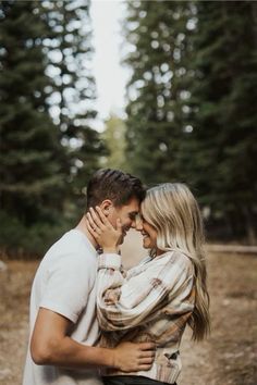 a man and woman embracing each other in the woods