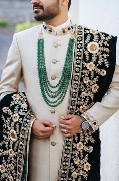 a man wearing a white and black outfit with green beads