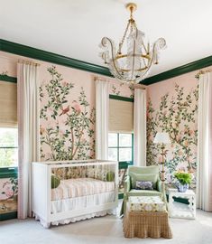 a baby's room decorated in pink and green with floral wallpaper, chandelier and crib