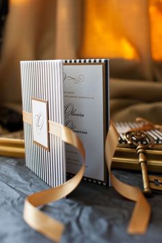 an open book on a table with a ribbon around it and a candle in the background