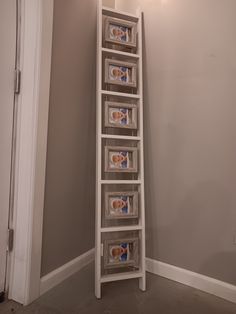 a tall white shelf with several boxes on it in a corner next to a door