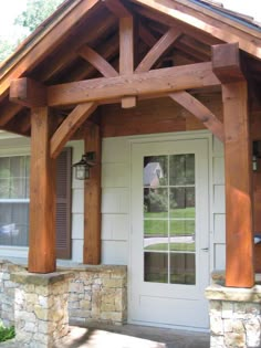 the front porch is covered in wood and has stone columns, pillars, and windows