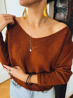 a woman wearing a brown sweater and gold earrings