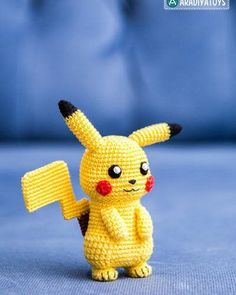 a yellow crocheted pikachu holding a sign