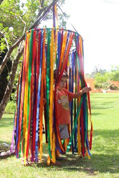 a young boy standing in front of a pole with streamers on top of it