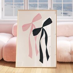 a framed art piece with pink and black ribbons hanging on the wall next to a couch