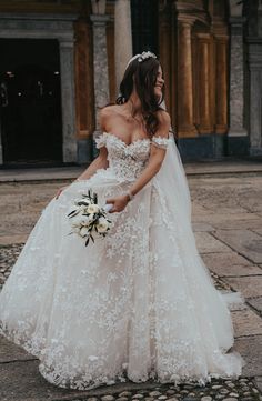 a woman in a wedding dress is standing outside