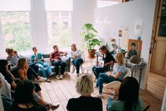 a group of people sitting in a living room talking to each other on couches