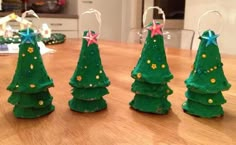 three small green christmas trees sitting on top of a wooden table