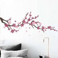 a bed room with a neatly made bed and a wall sticker that has purple flowers on it