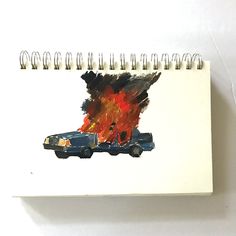 a spiral notebook with a drawing of a car on fire in the back and flames coming out of it