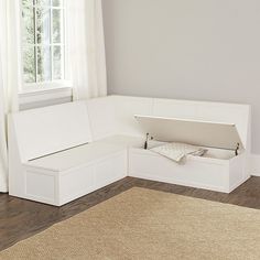 a white corner sofa in front of a window with an area rug on the floor