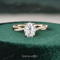 a diamond engagement ring sitting on top of a green velvet box