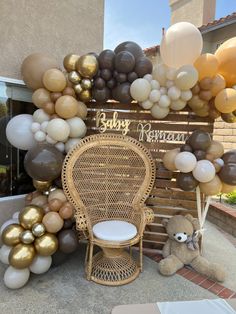 a baby shower is decorated with balloons and a teddy bear sitting in a chair next to it