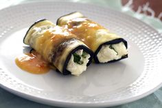 a white plate topped with two rolls covered in cheese and sauce