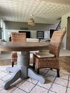 a dining room table with wicker chairs and a rug on the floor in front of it