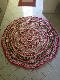 a pink and green rug on the floor in a room with white tile floors, an area rug that looks like a flower