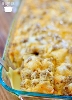 a casserole dish with meat and cheese in it on a wooden table next to a fork