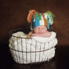 a newborn baby wearing a colorful hat in a basket