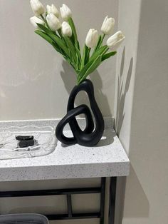 a vase with white flowers sitting on a table next to an earbud plug