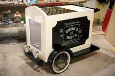 an ice cream cart with wheels is parked in a garage next to other items on the floor