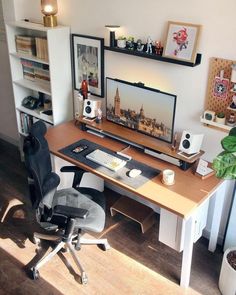 a desk with a computer, speakers and bookshelf in the corner next to it