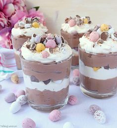 three glasses filled with desserts on top of a table