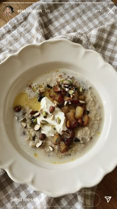 a white bowl filled with oatmeal and nuts on top of a table