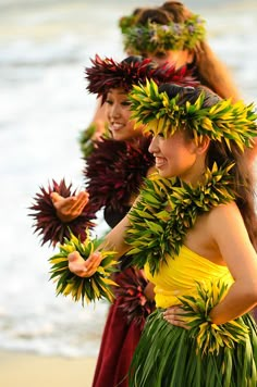 three beautiful women in grass skirts standing on the beach