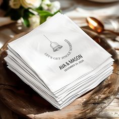 a stack of white napkins sitting on top of a wooden plate next to flowers