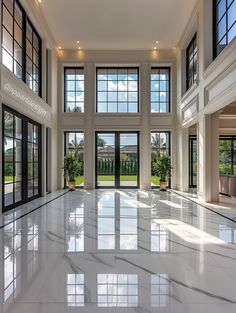 an empty room with large windows and white marble flooring in front of the doors