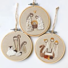 three hand embroidered christmas ornament hanging from twine hoops on white surface